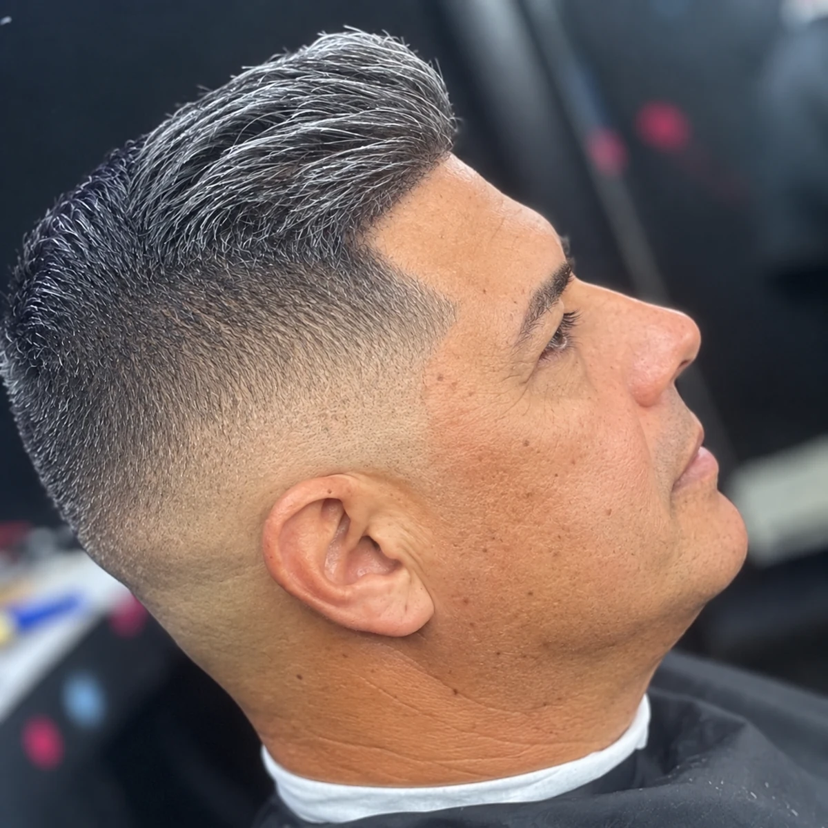 Cheveux poivre et sel coiffés sur le côté avec fondu court